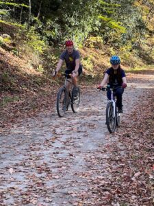 Carl and Sarah riding bikes on a forest trail